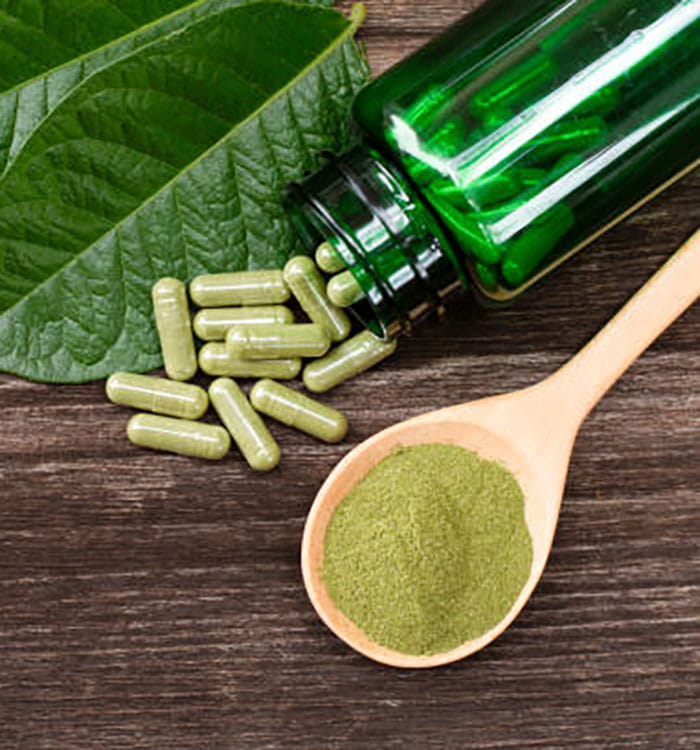 Picture of herbal substance kratom in pill and power form on spoon.