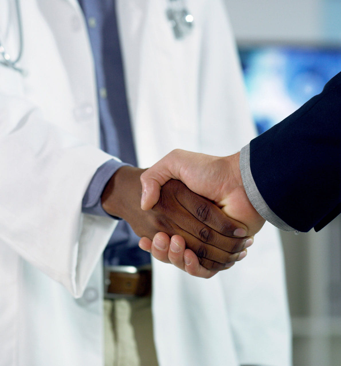 Shot of two unrecognizable people one is physician coat the other in a mens blazer shaking hands.