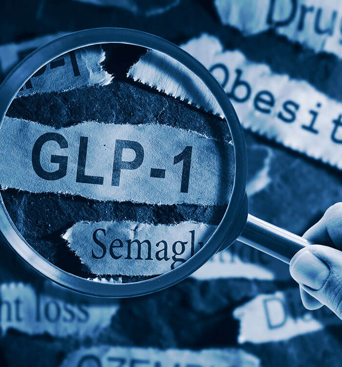 GLP-1 related drugs newspaper headlines with hand and magnifying glass.