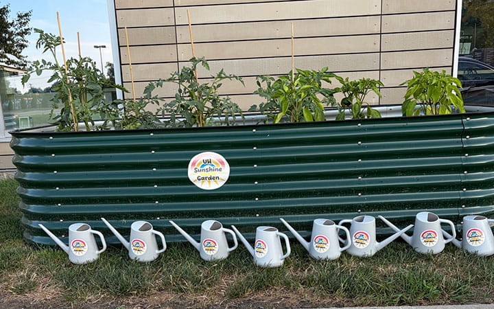 The raised container garden with watering cans in front of at the UH Rainbow Center for Women & Children Midtown Clinic.