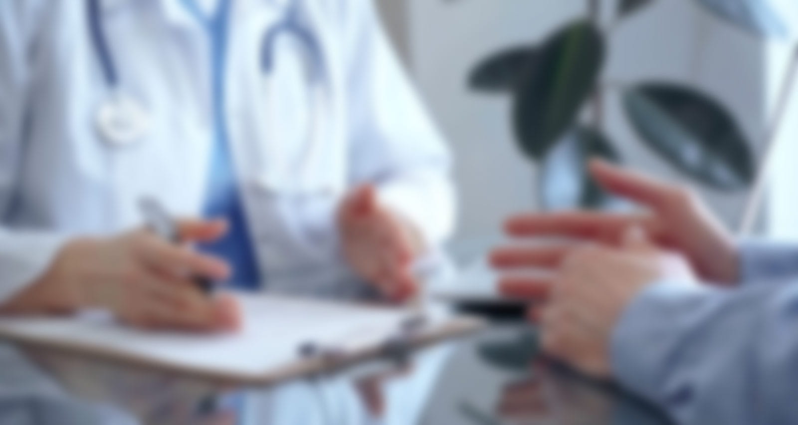 A female doctor wearing a white medical coat is consulting with a patient in a clinic office