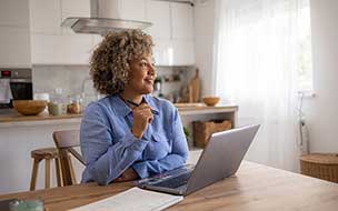 Happy female entrepreneur brainstorming while working on a computer at home