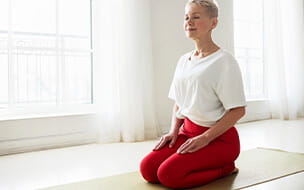Senior female sitting in virasana posture with eyes closed practicing meditation