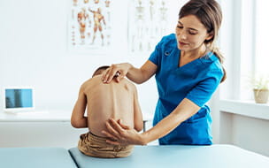 Female doctor performing a Scoliosis examination on a child in the office