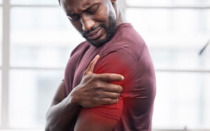 Close up of a man holding shoulder in pain