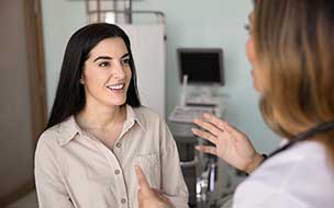 Positive young Latin woman talking to doctor in office