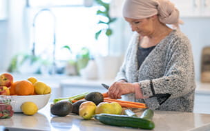 Woman with cancer cooks a healthy meal by the kitchen counter