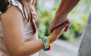 Autistic child holding hands with their mother