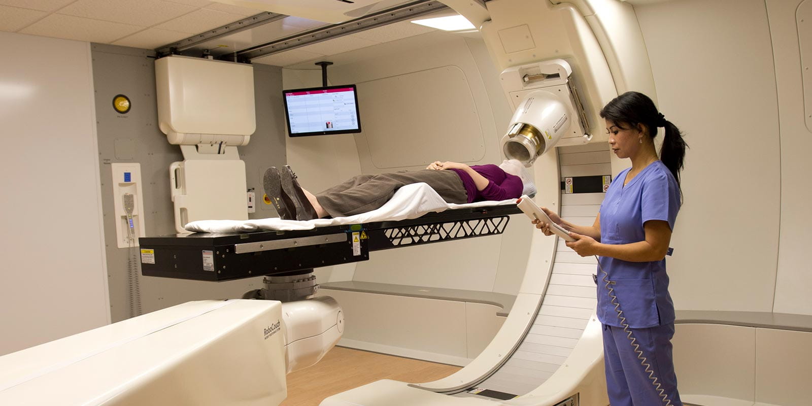 Woman with nurse beginning proton therapy.