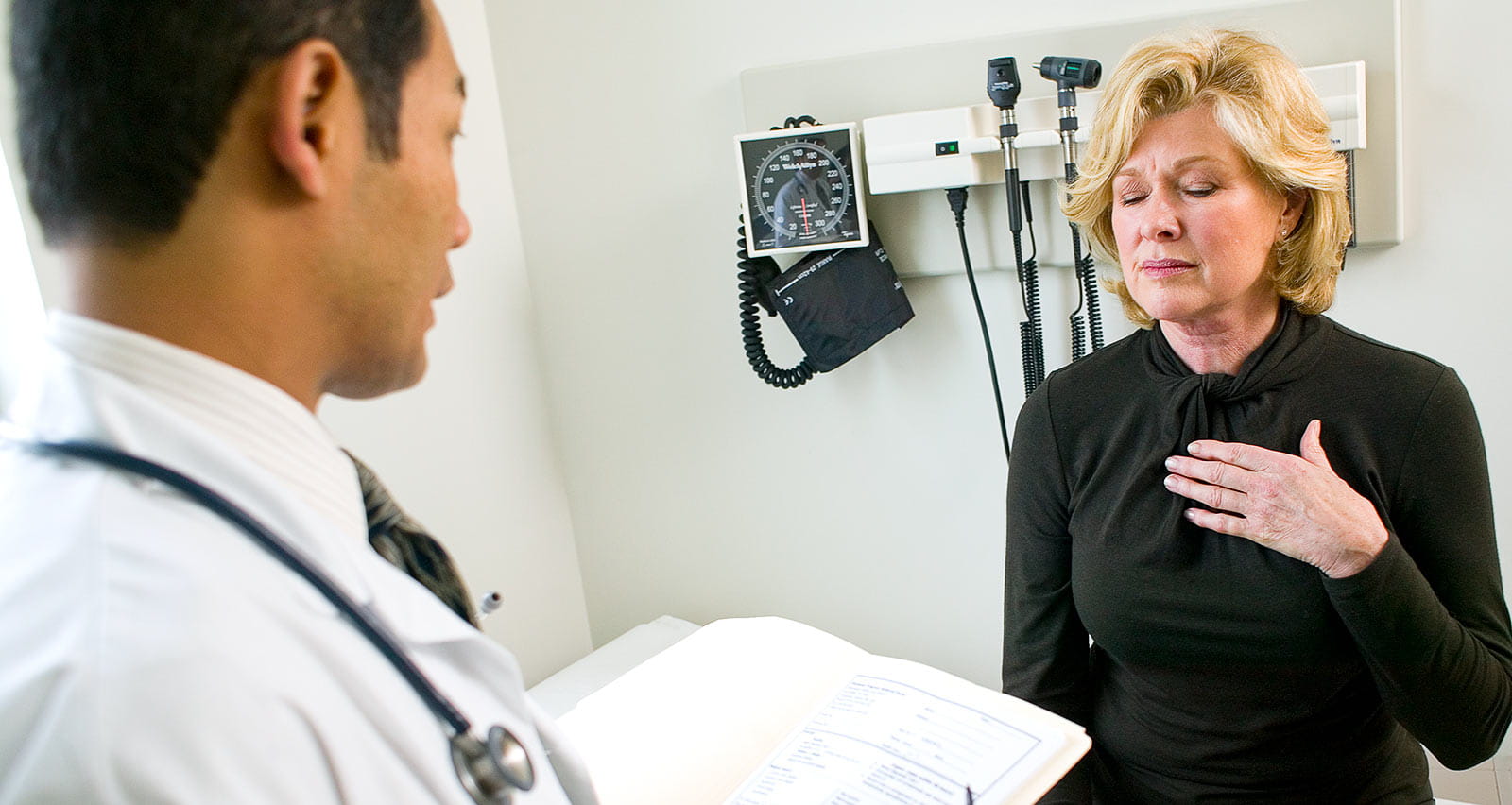 Woman suffering from heartburn in exam room