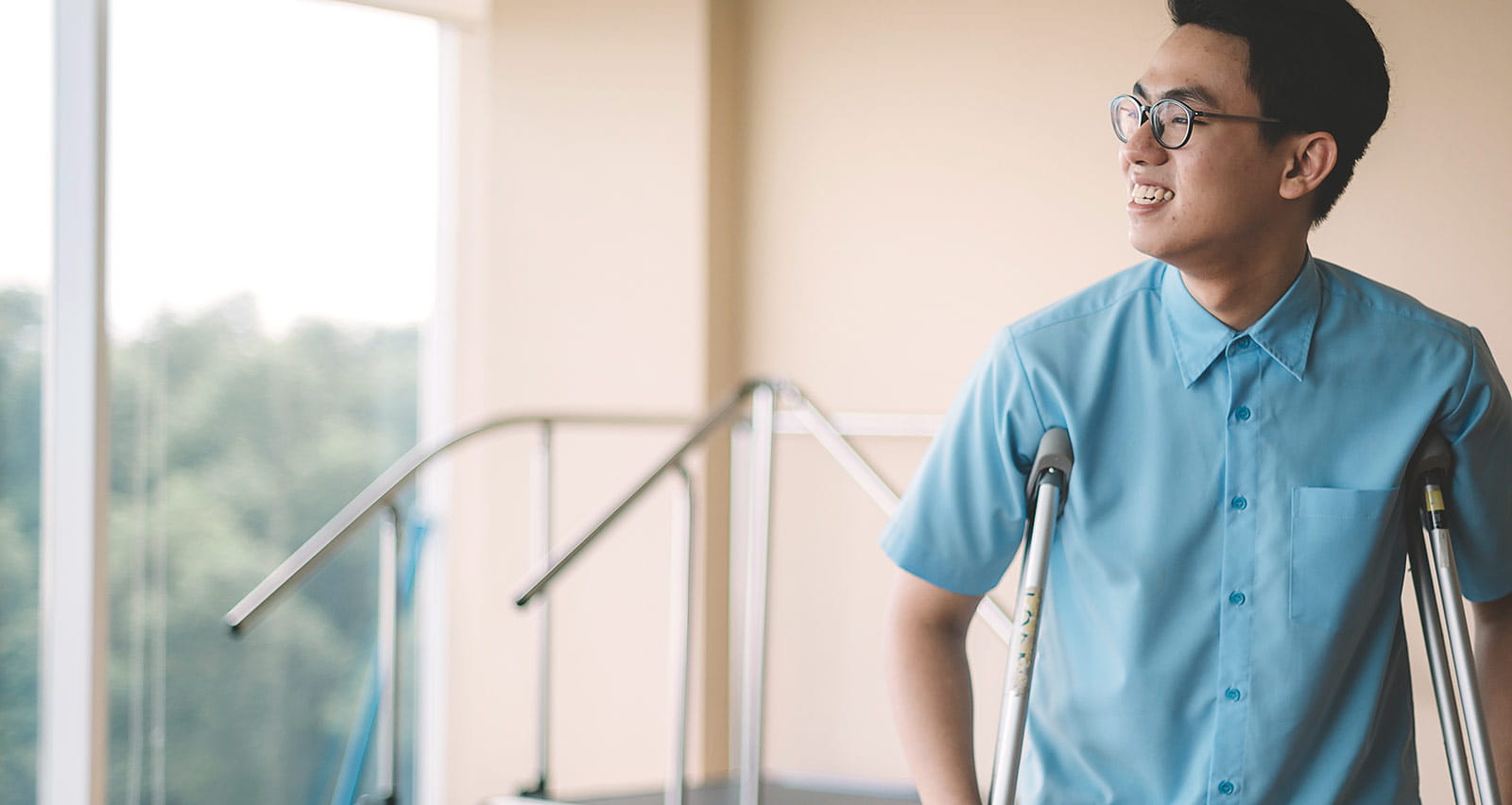 A male patient recovering from his leg injury and walking with crutches in the hospital