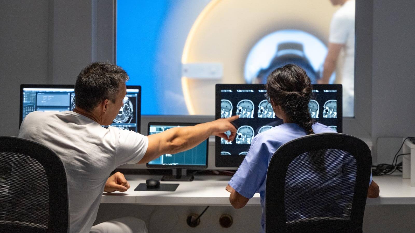 Two MRI radiologists sitting in the control room and operating the MRI scanner