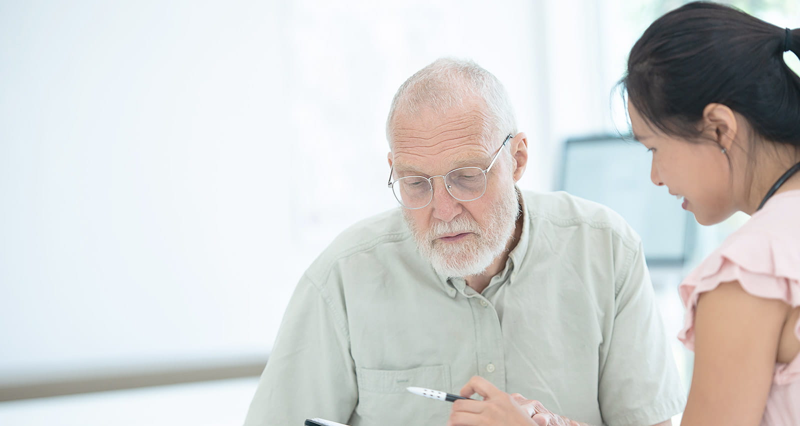 A medical professional explains changes in healthcare coverage to an elderly male Caucasian patient