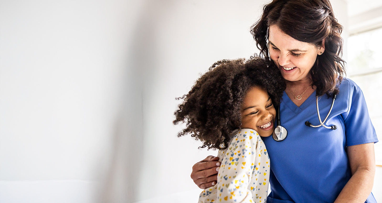 A young girl embraces a nurse in a medical office