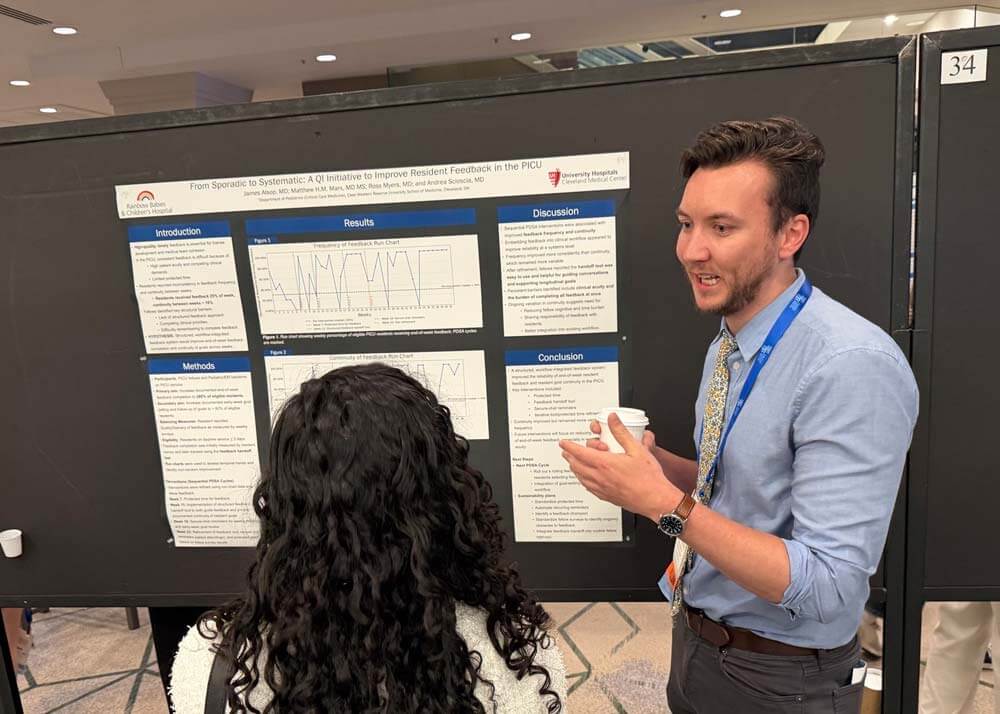 male fellow presenting research poster