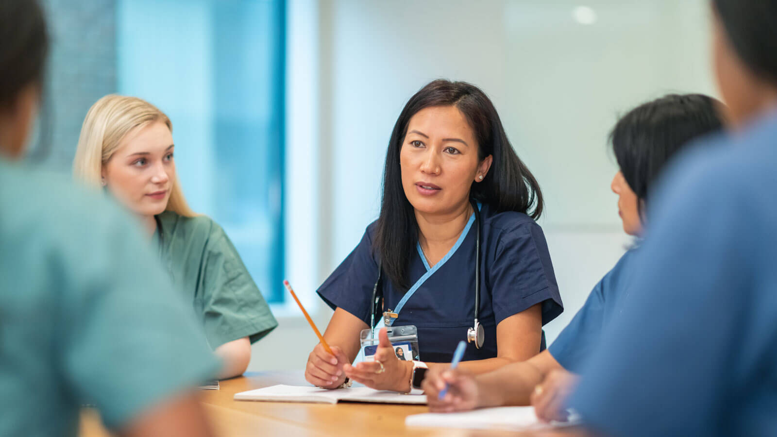 An Asian woman leads a meeting with her medical team