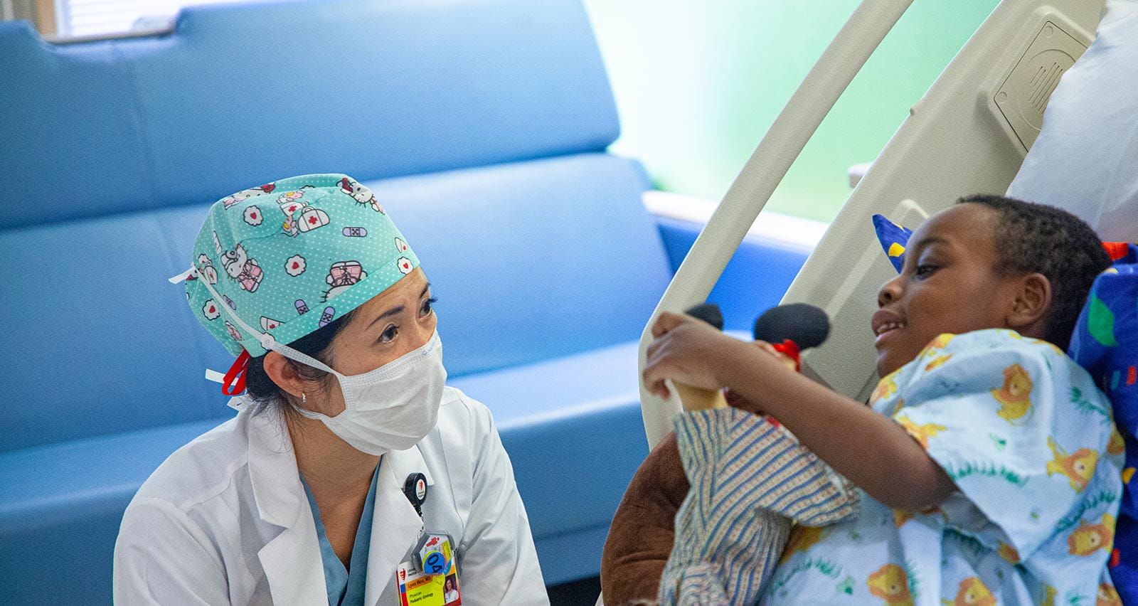 Lynn Woo, MD sits at her young patient’s bedside
