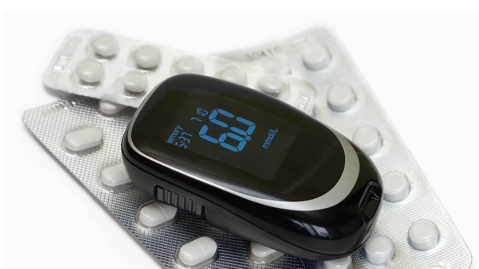 Medical blood glucose meter and pills on white background