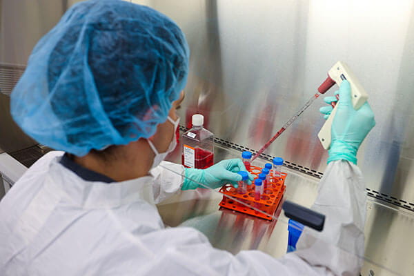 researcher in scrubs using pipette in the Wesley Center for Immunotherapy