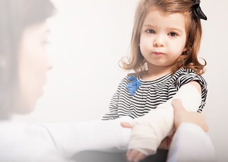 Young girl getting her arm tended to by her pediatrician