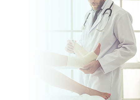 Male doctor wrapping bandage around ankle