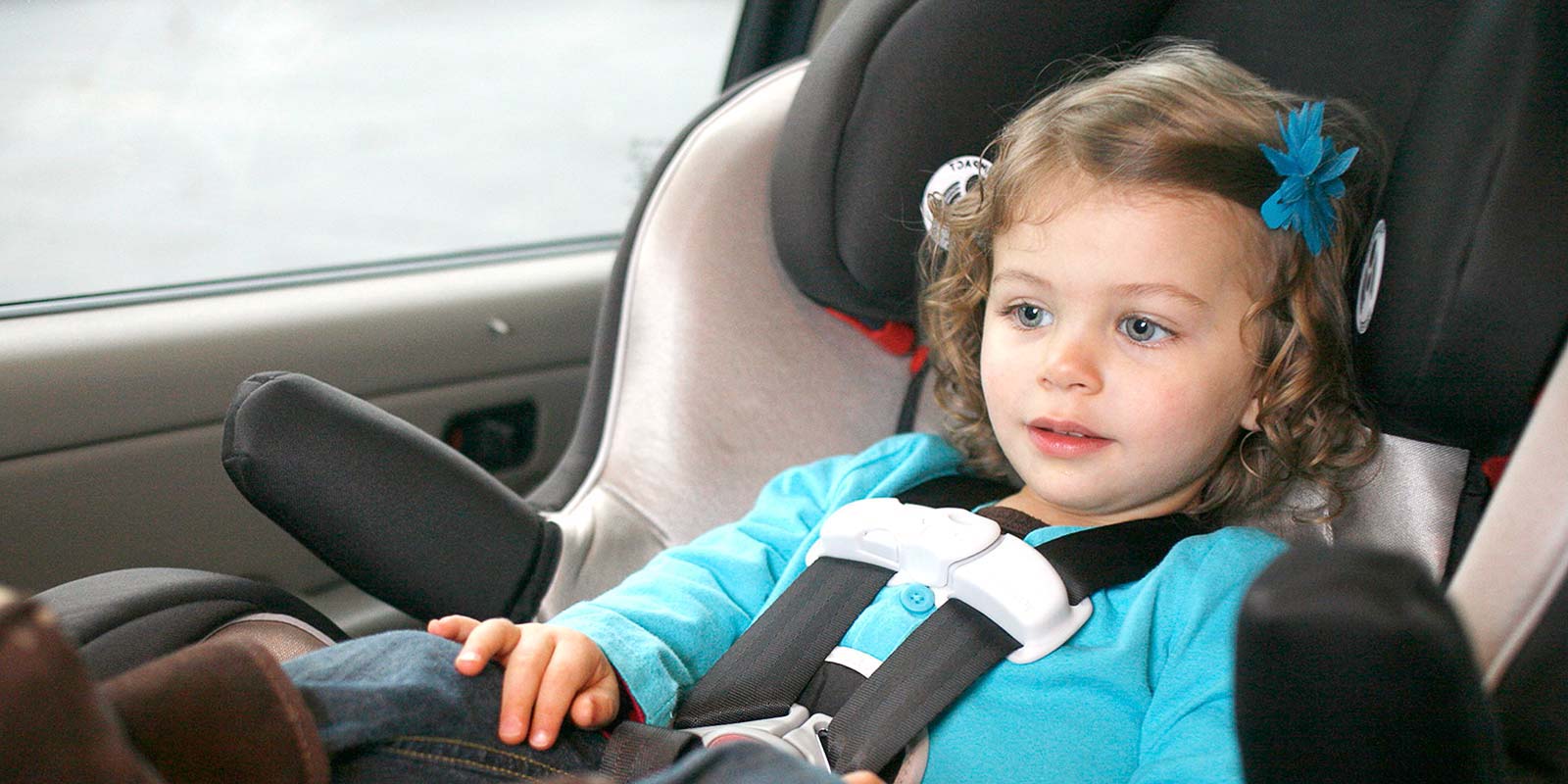 Young girl fastened into protective car seat