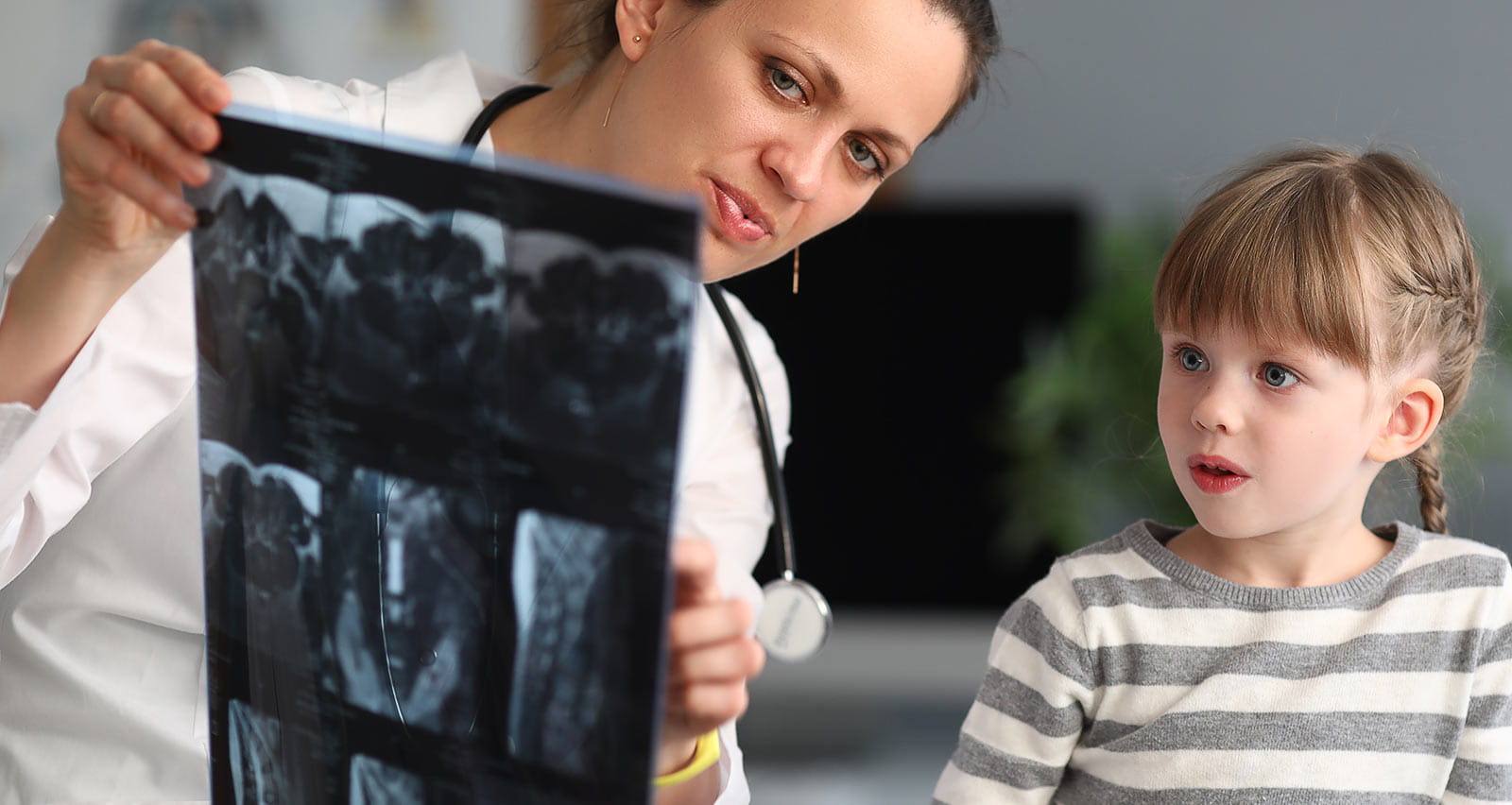 A female doctor shows child patient an x-ray in a clinic