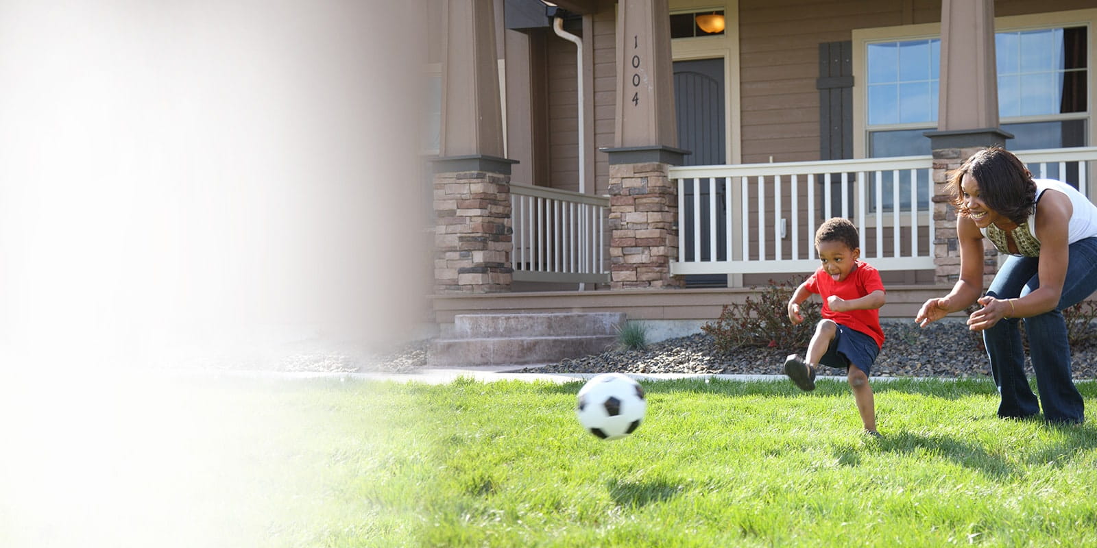 Son kicking soccer ball with mother.