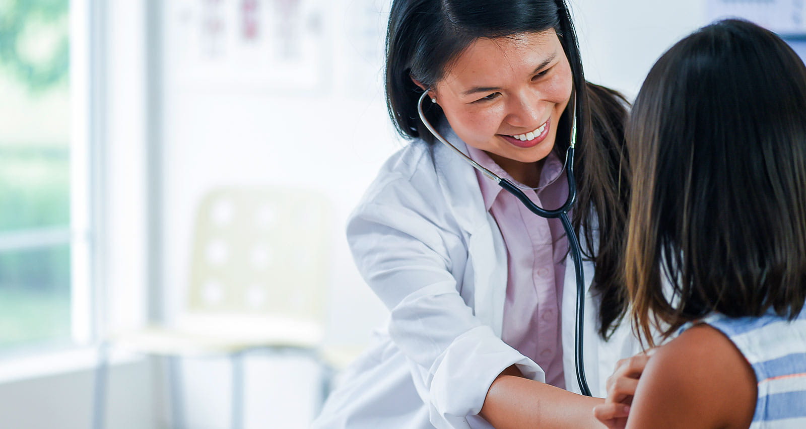 A female pediatric doctor checks a child's heartbeat with a stethoscope