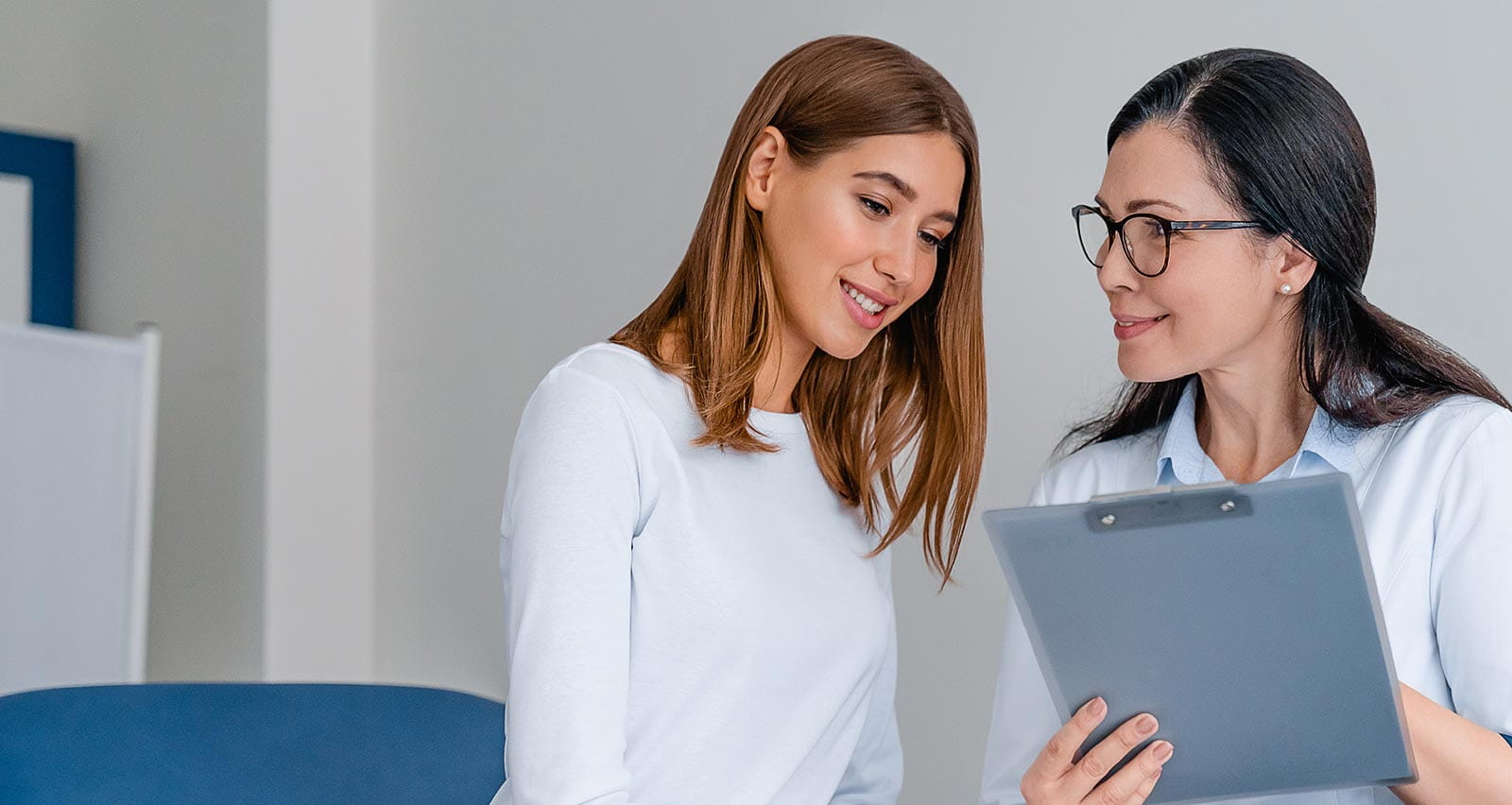 A smiling doctor consults with her young female patient