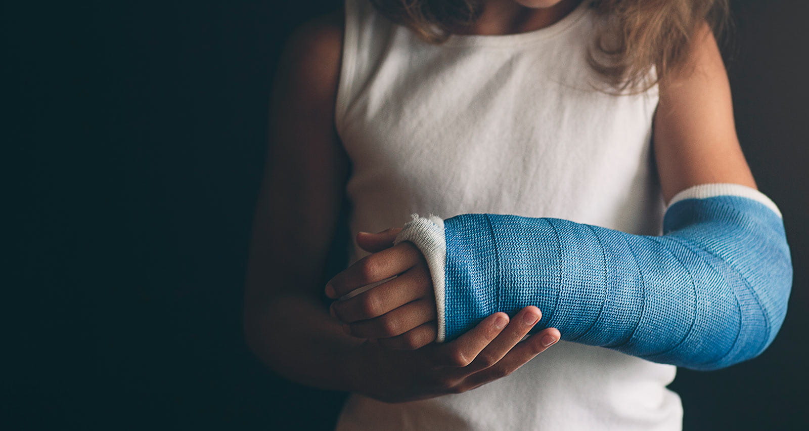 A young girl holds arm in blue cast