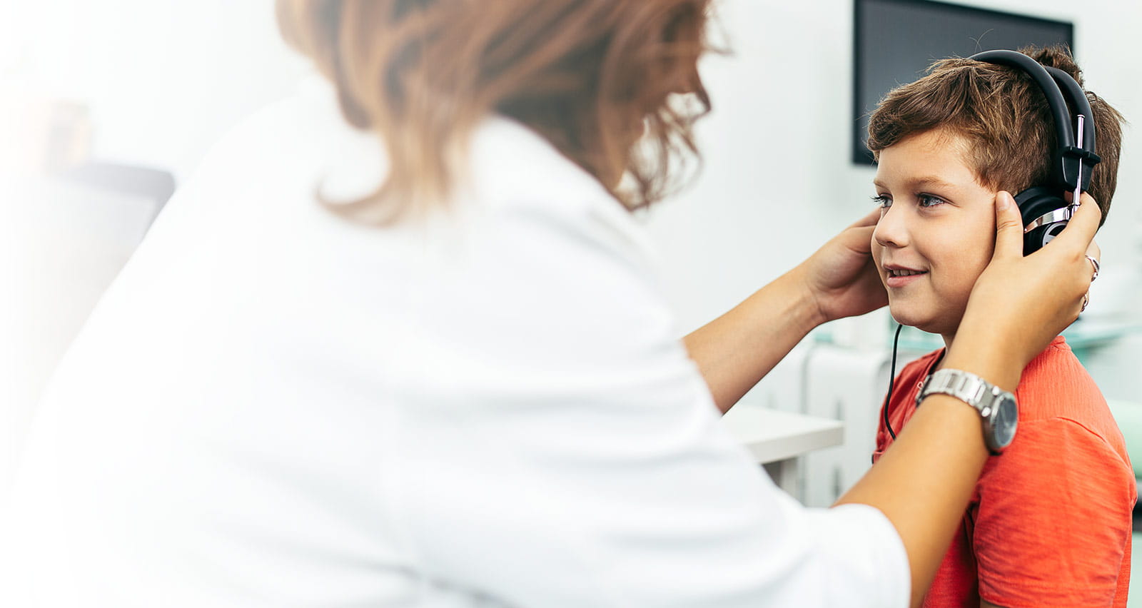 A young boy wears headphones as part of a checkup in his otolaryngologist's office