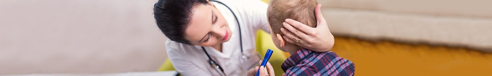 Female doctor checking boy's ears.