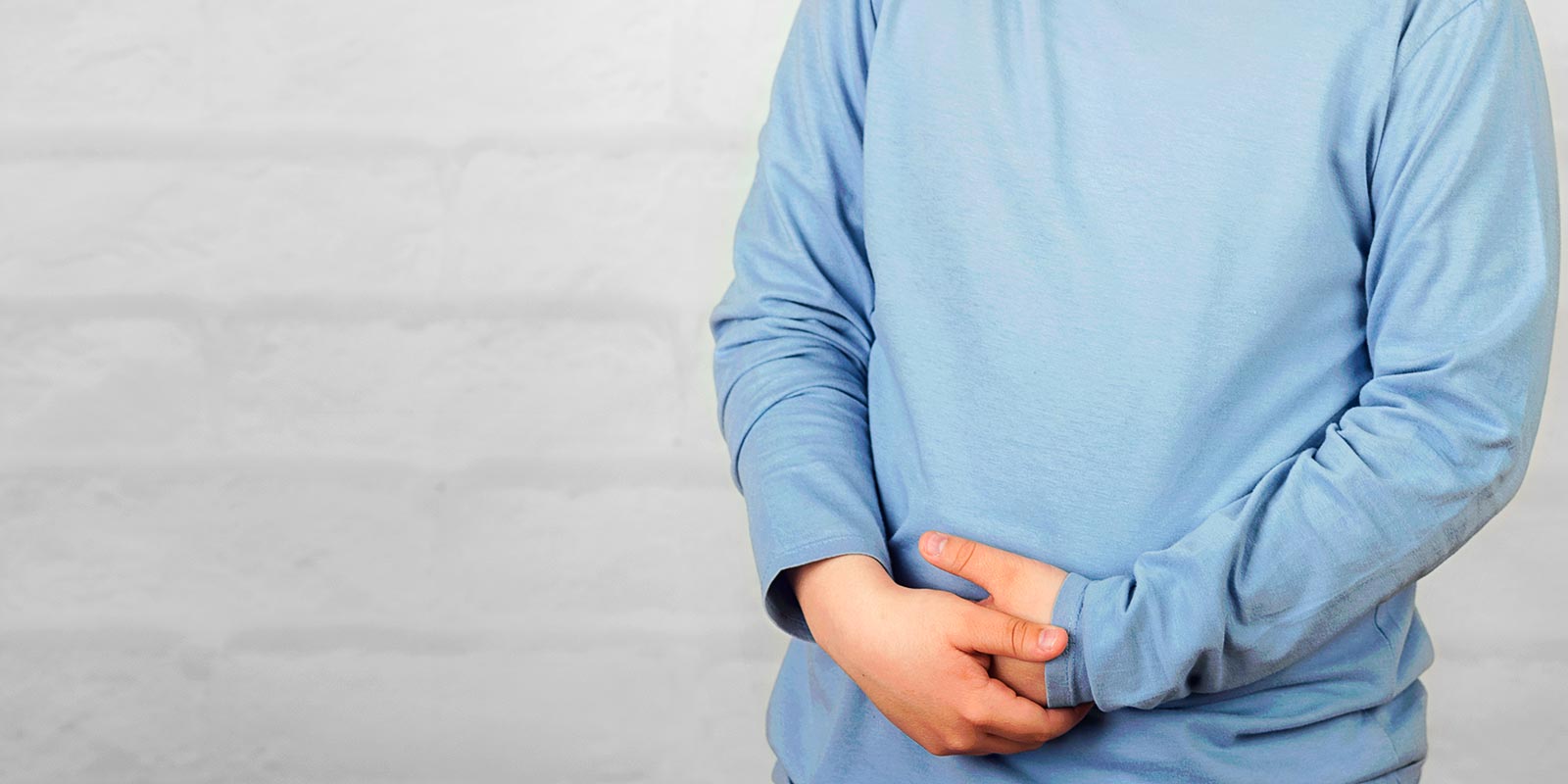 A child with constipation standing against brick background