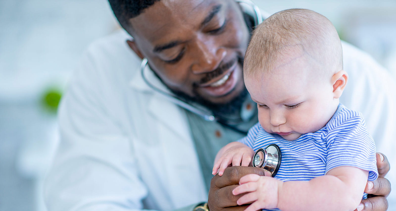 A baby boy is having his heart checked by a male doctor