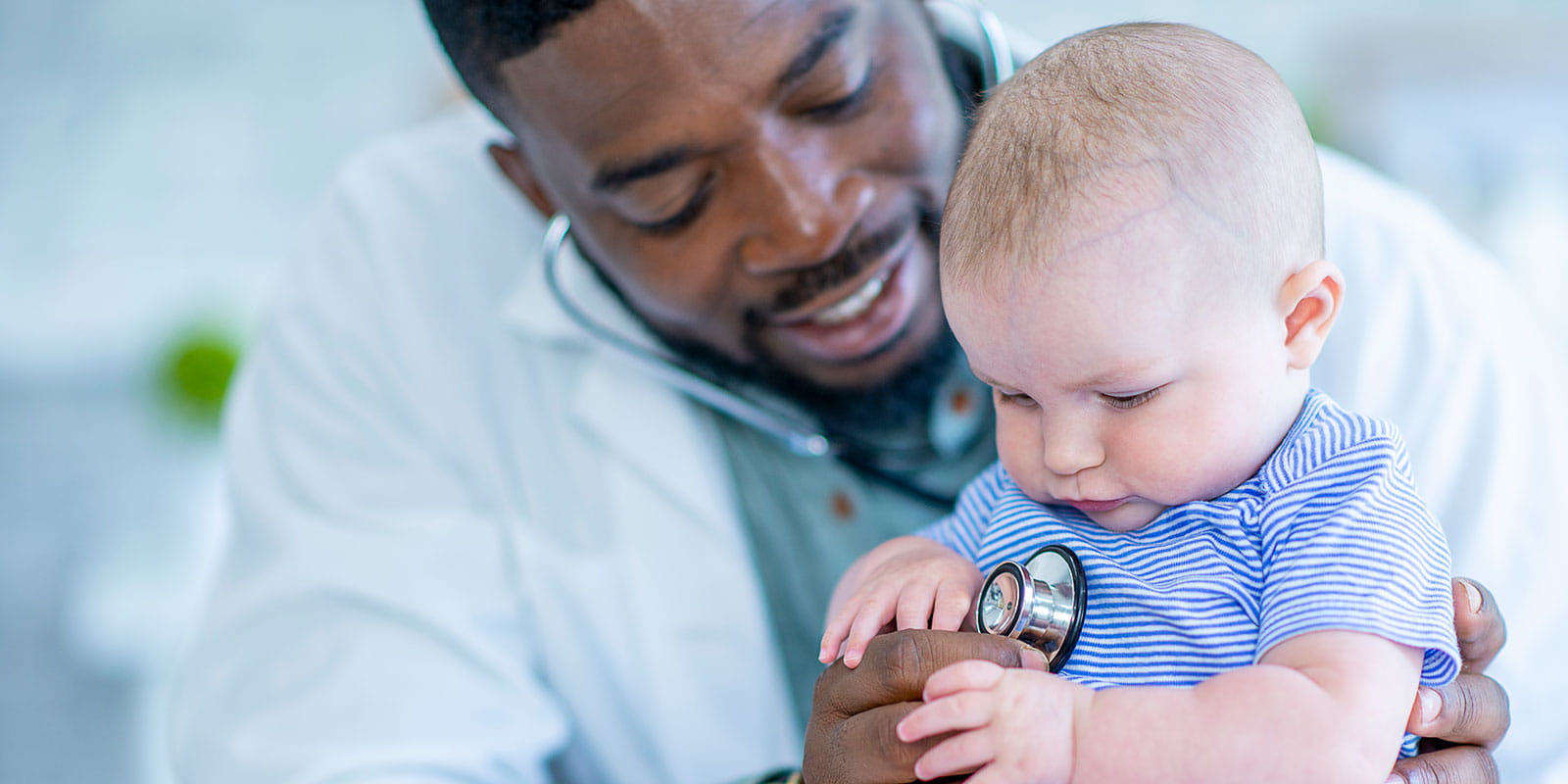 A baby boy is having his heart checked by a male doctor