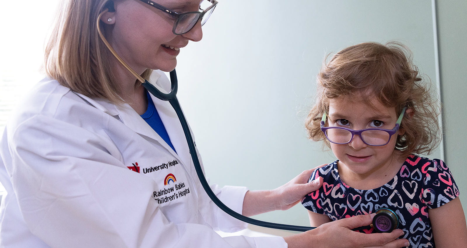 A provider listens to a young patient’s heart with a stethoscope at the The UH Rainbow Heart Center