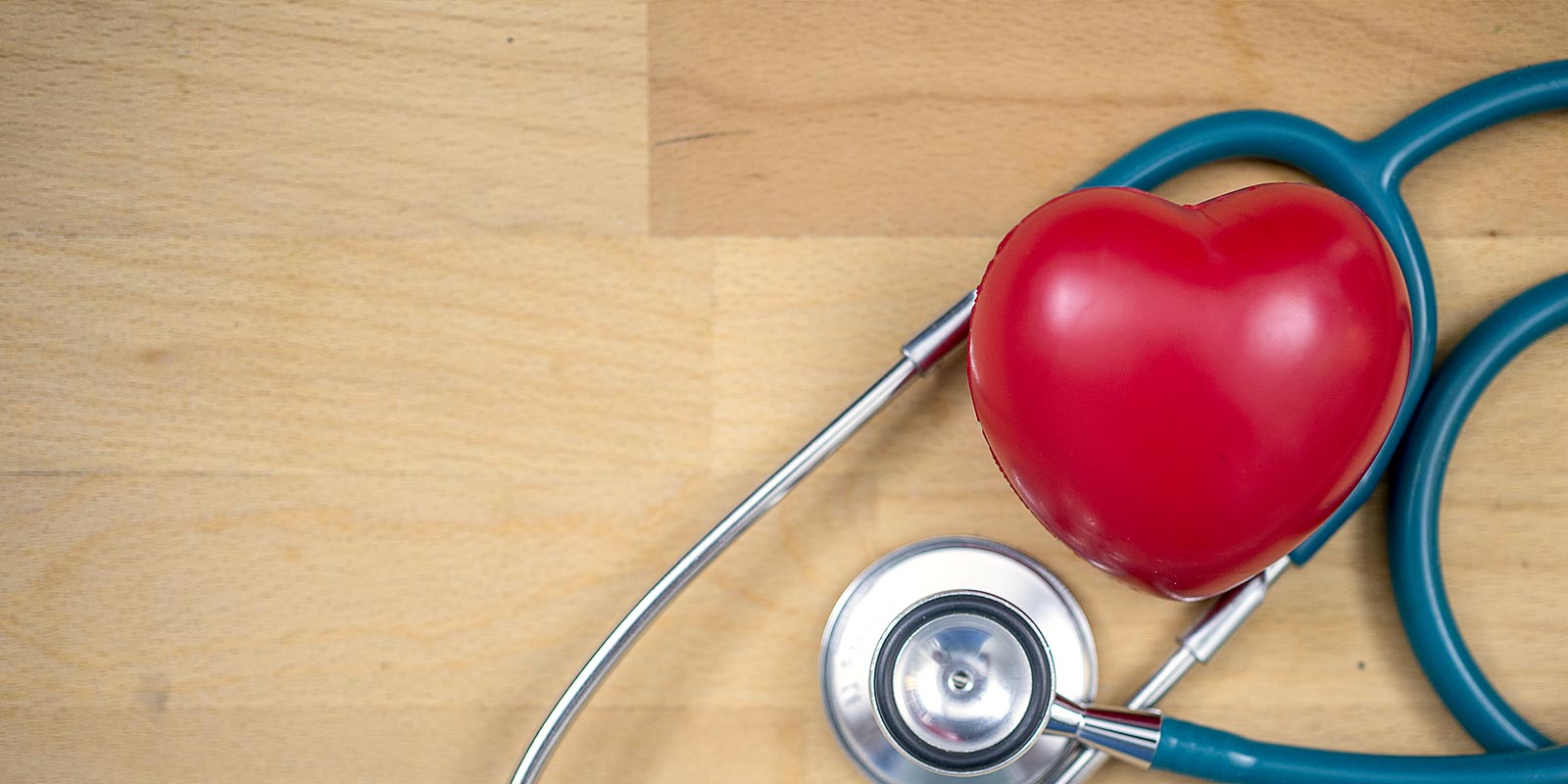 A stethoscope winding around a red wooden heart