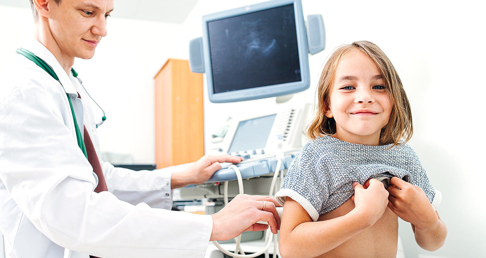 Doctor performing ultrasound scan on a little girl, checking her kidneys while she's sitting still