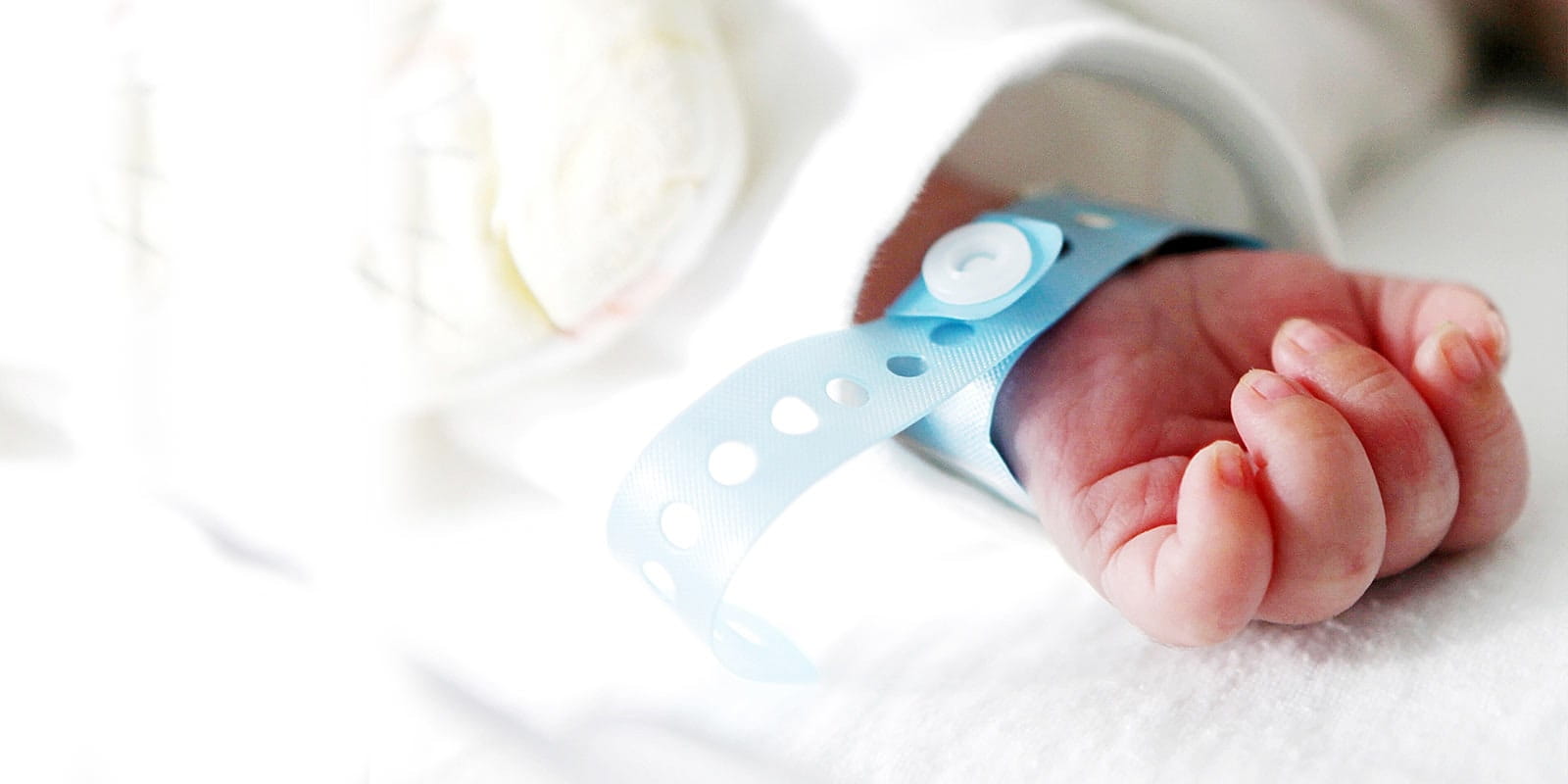 Newborn baby laying in crib in Neonatal Intensive Care Unit.