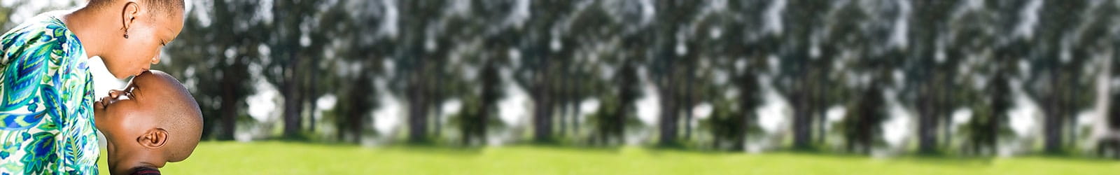 Mother kissing son's forehead in a park.