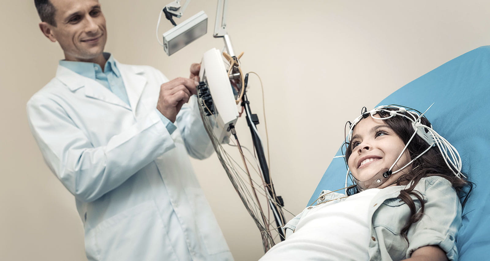 Cheerful positive girl lying on the medical bed being prepared for EEG