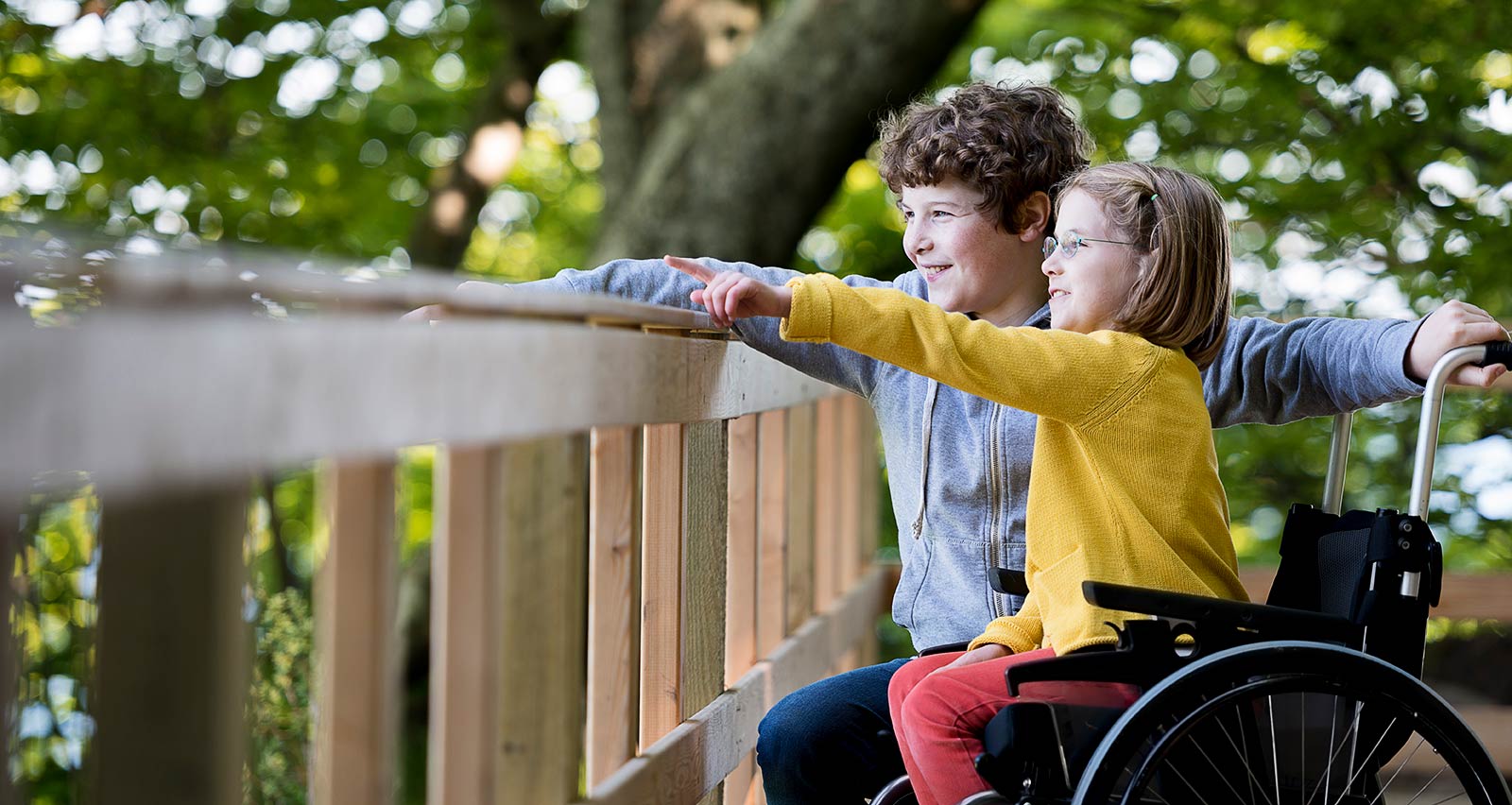 Wheelchair bound eight year old girl and her 11 year old brother, looking out at the view from a purpose built wheelchair access point