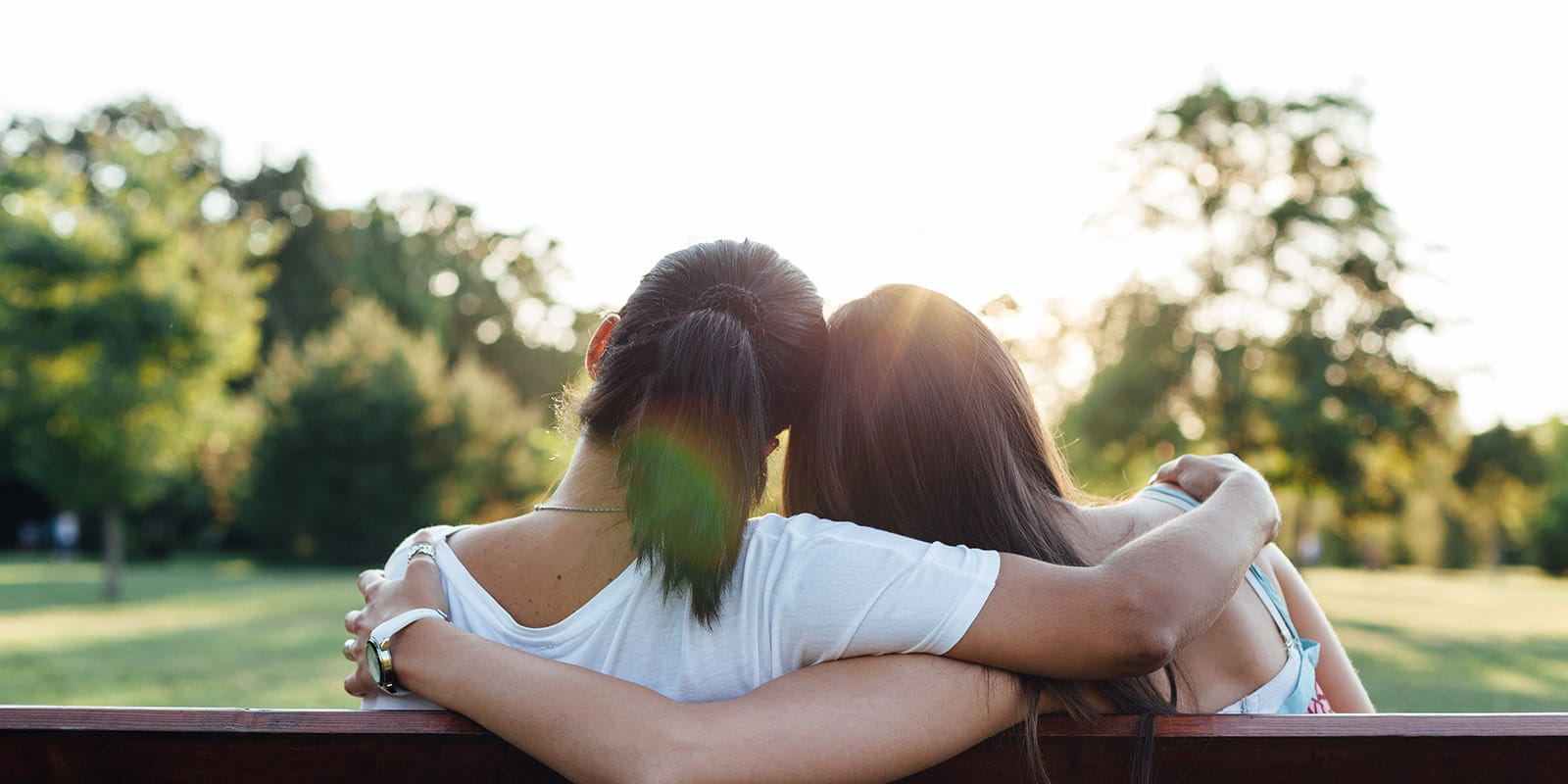 Mother and daughter watching sunset in park.