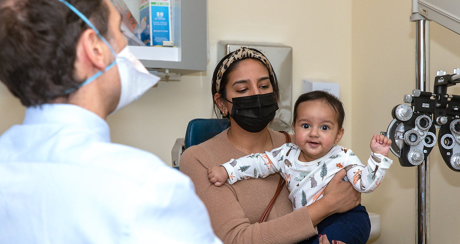 A mother holds her child during an eye exam
