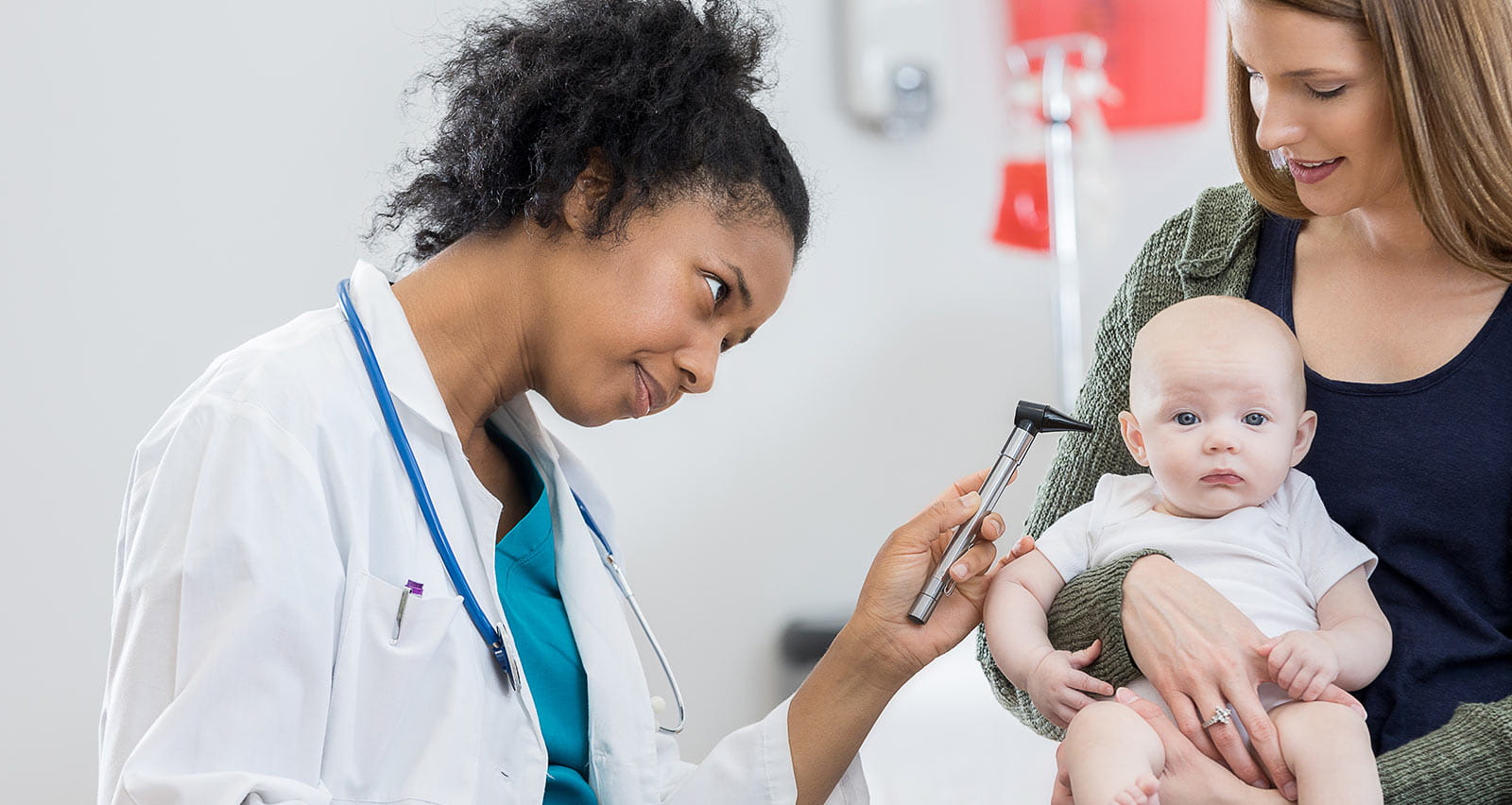 A female pediatrician uses an otoscope to look in baby's ear