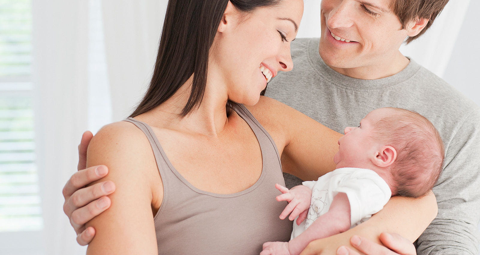 Smiling parents hold their baby