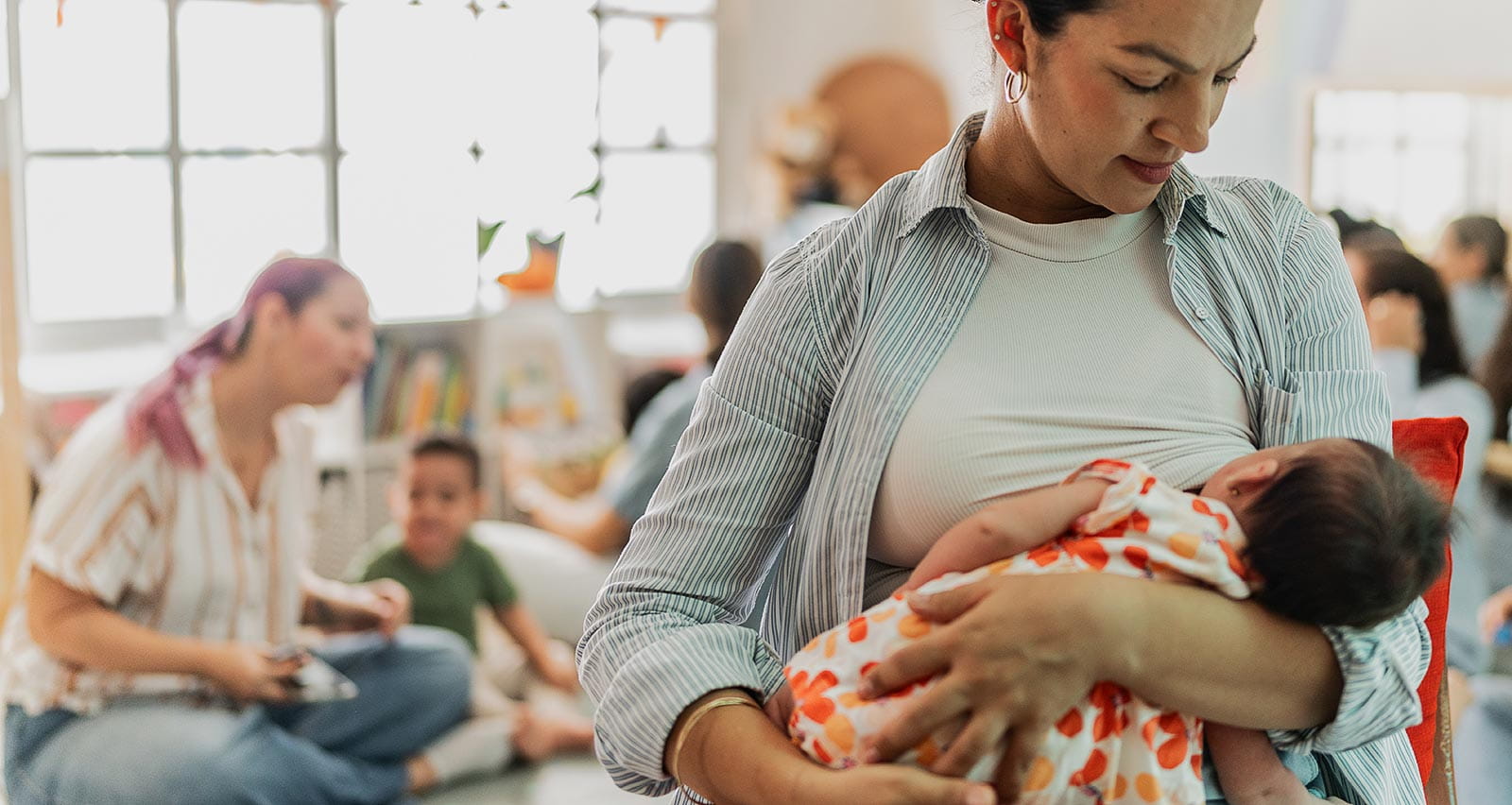 A woman breastfeeding her baby girl while in a mother's group
