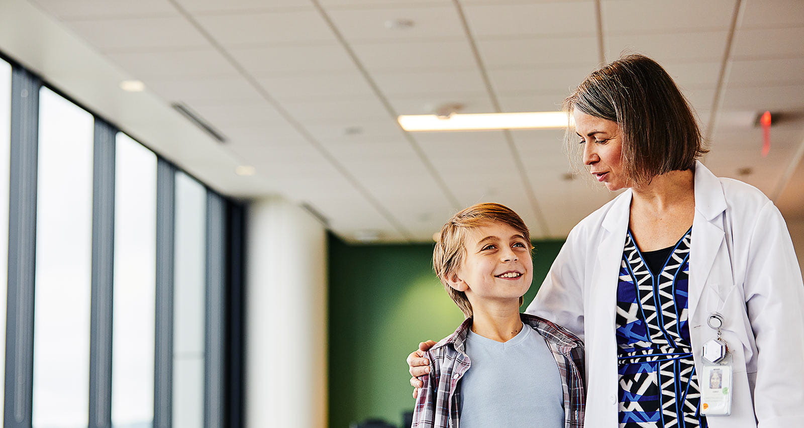 Female doctor talking to smiling boy in hospital