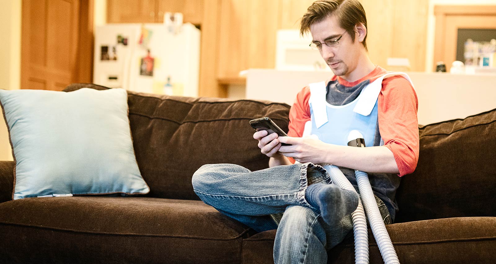 A young man at home uses a machine to help with mucus buildup from cystic fibrosis
